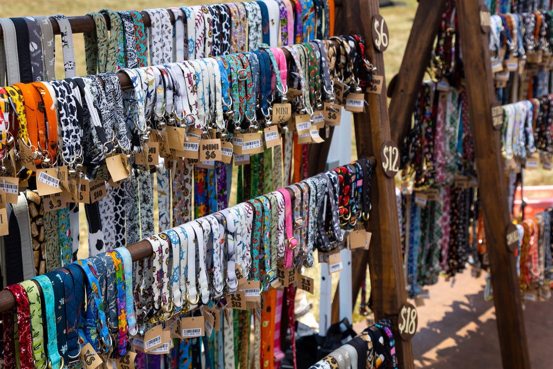 Multi colored dog collars hung over a 4 tier wooden display stand