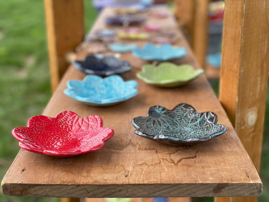 Photo of many different colored spoon rests sitting on top of a wooden board.