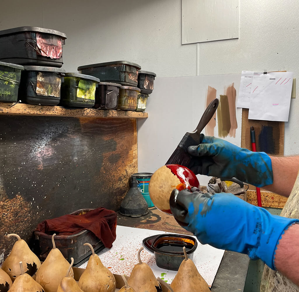 Employee applying dye on a gourd at Meadowbrooke Gourds