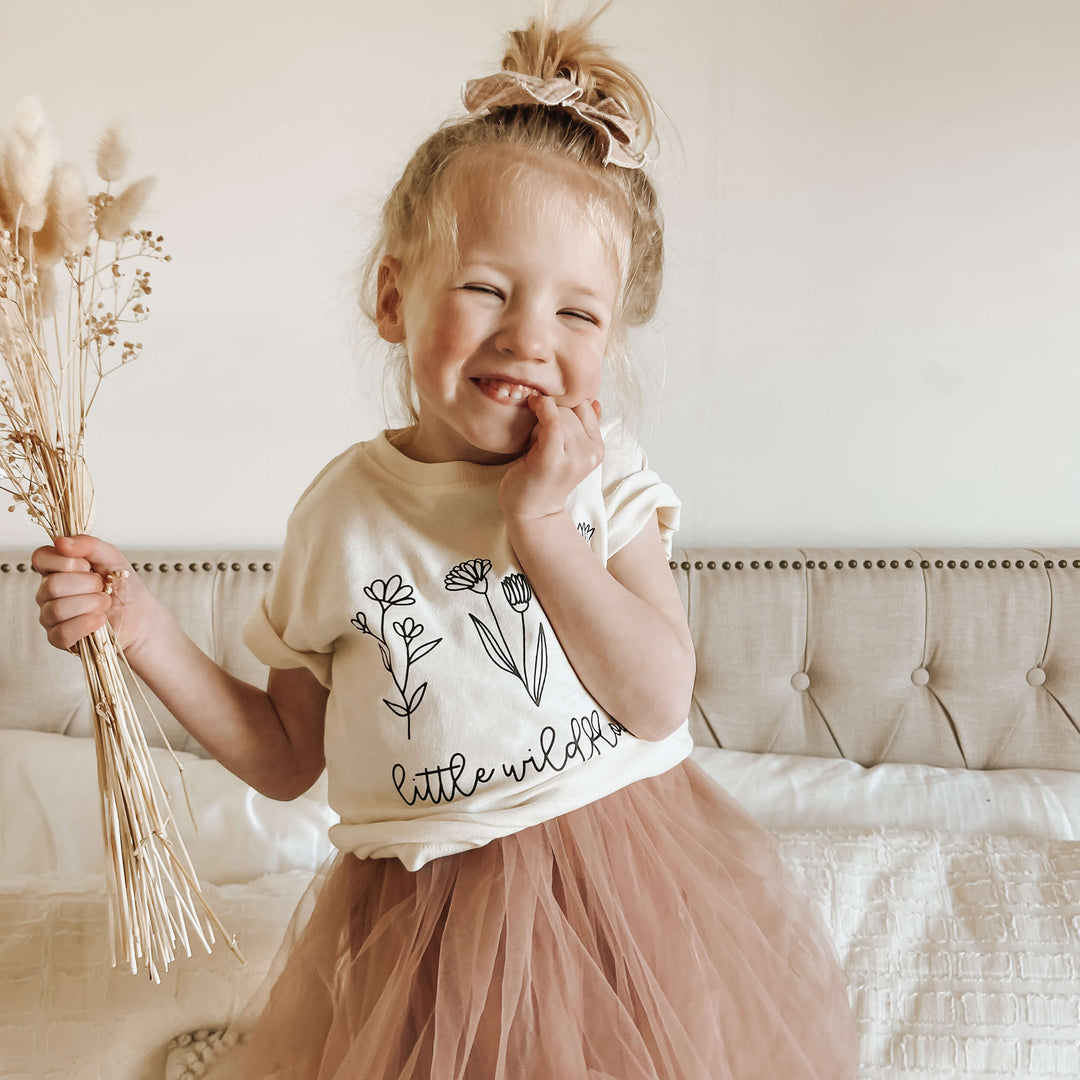 little blonde toddler holding dried flowers
