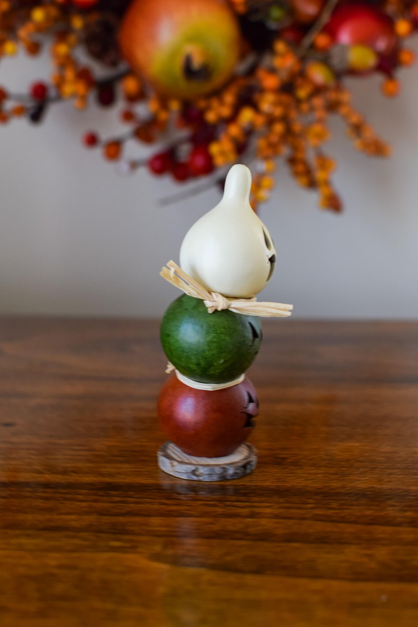 Decorative Gourd with a white top, green middle, and orange bottom on a wooden biscuit.